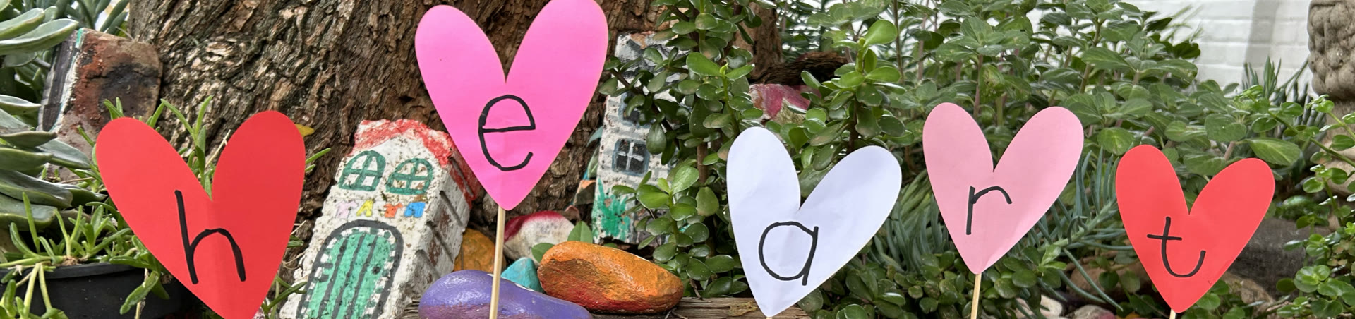 bursary-banner-2026 Hearts made by the children spelling the word heart, on sticks in the school garden